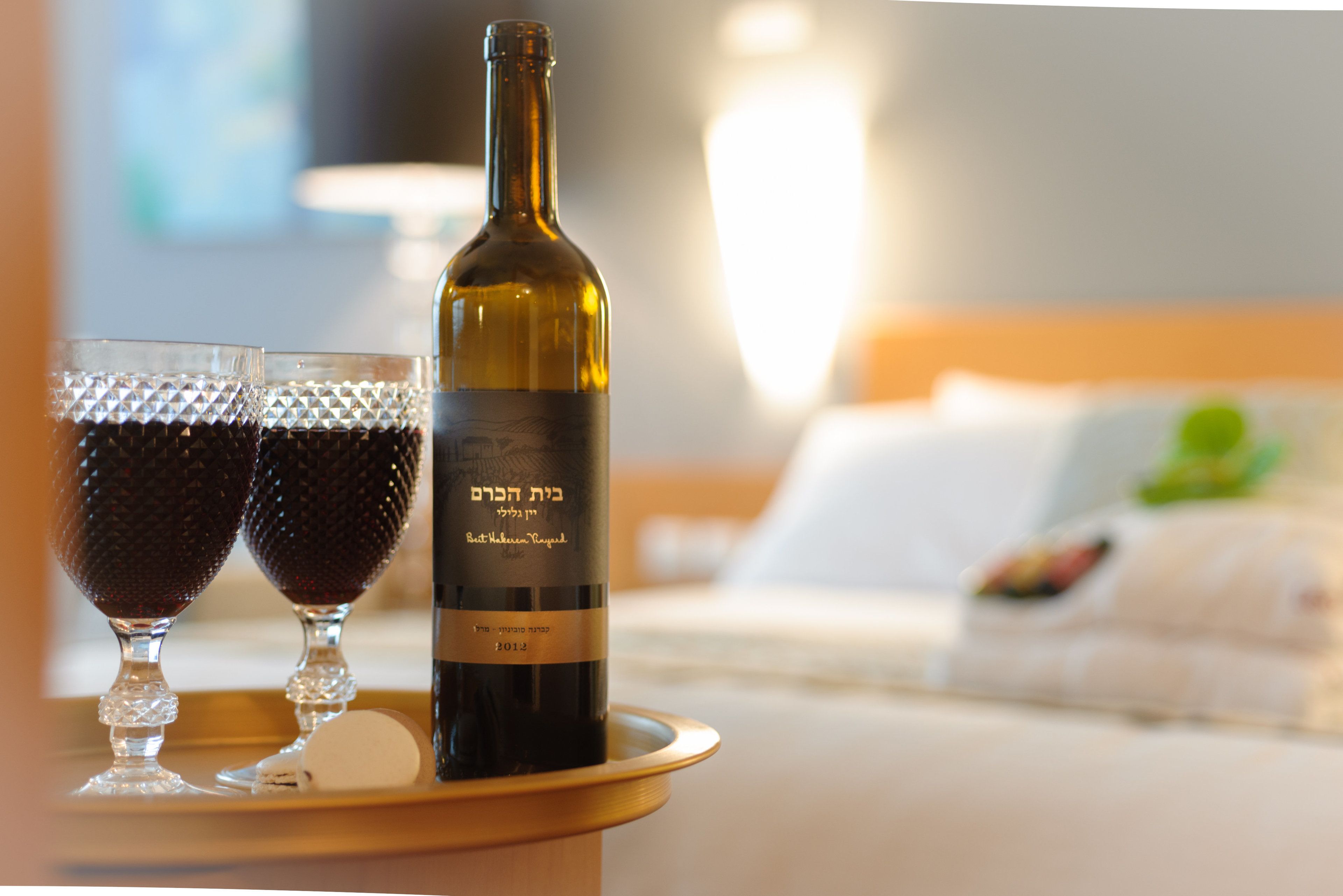 A bottle of wine on a tray with two glasses of red wine.