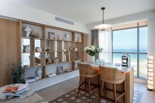 A modern kitchen with a bar area, large windows, and a view of the sea.