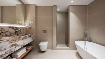 A modern bathroom with a marble vanity, a toilet, a walk-in shower, and a freestanding bathtub.