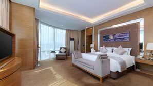 A modern hotel room with a large bed, a sofa, a TV, and a painting on the wall. - Gems Cube International Hotel Shenzhen (Shenzhen)