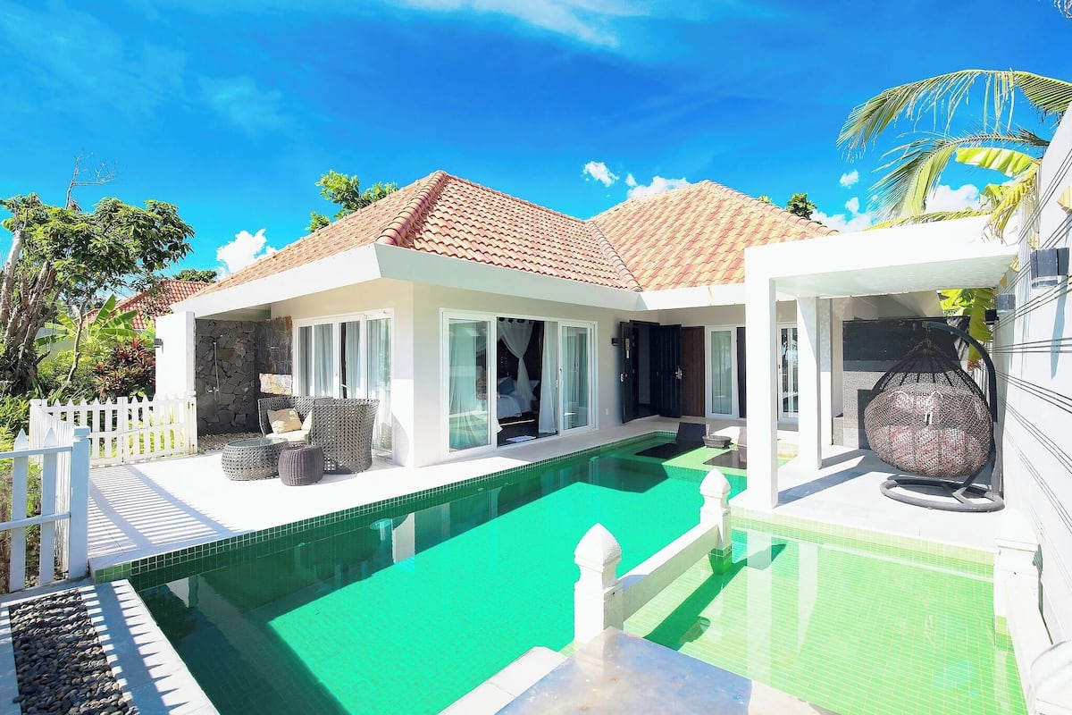 A modern house with a swimming pool, white exterior, and a tiled roof.