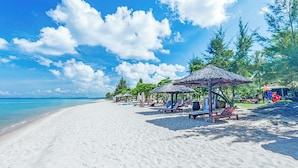 A beach with white sand, clear blue water, and a few umbrellas providing shade. - Mercury Phu Quoc Resort & Villas - Free Airport Transfer (Phu Quoc)