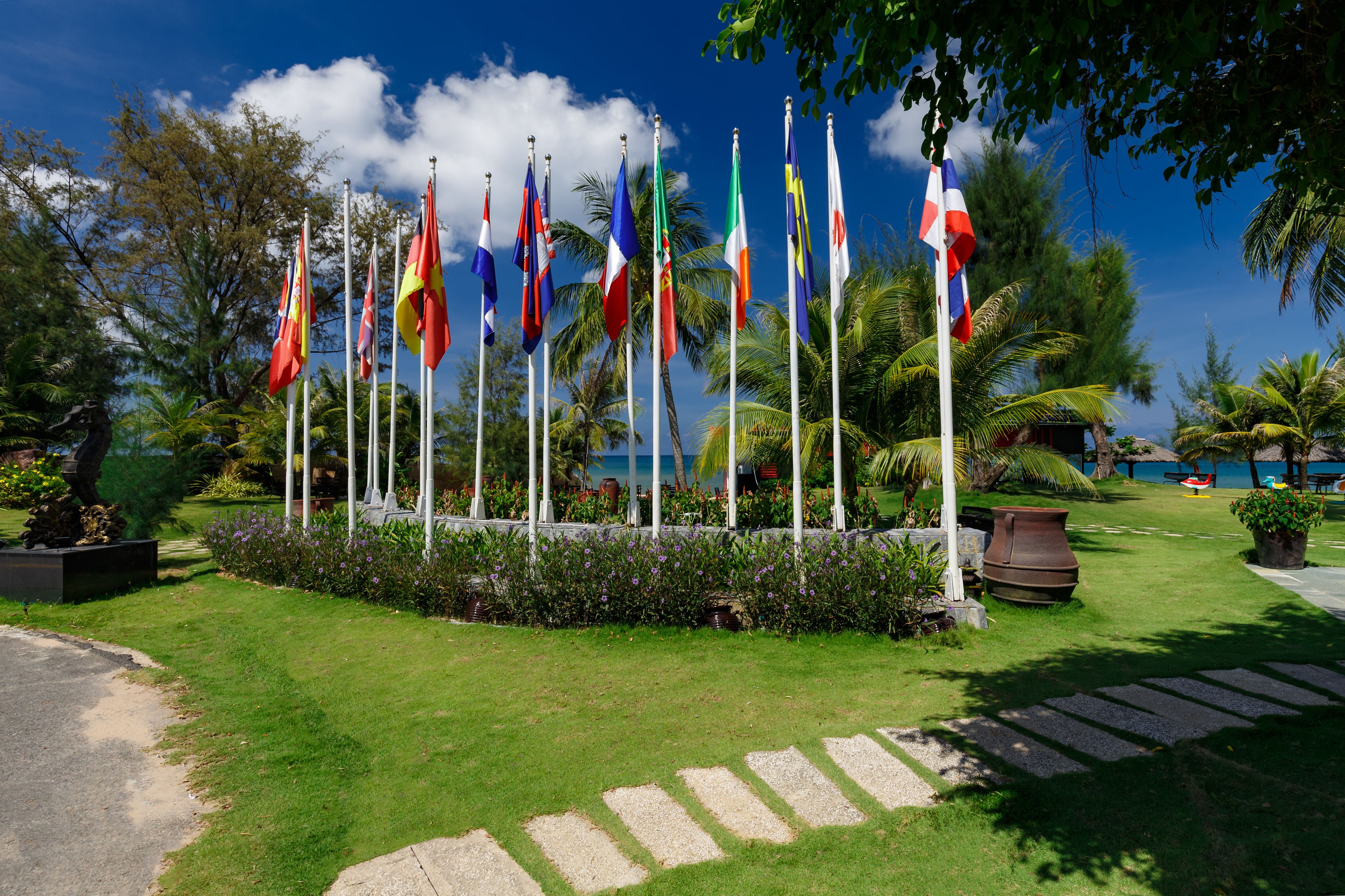 A grassy area with multiple flags and palm trees.
