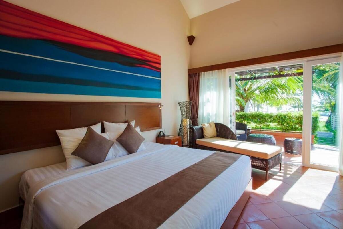 A hotel room with a large bed, a sofa, a table, and a view of the outdoors.