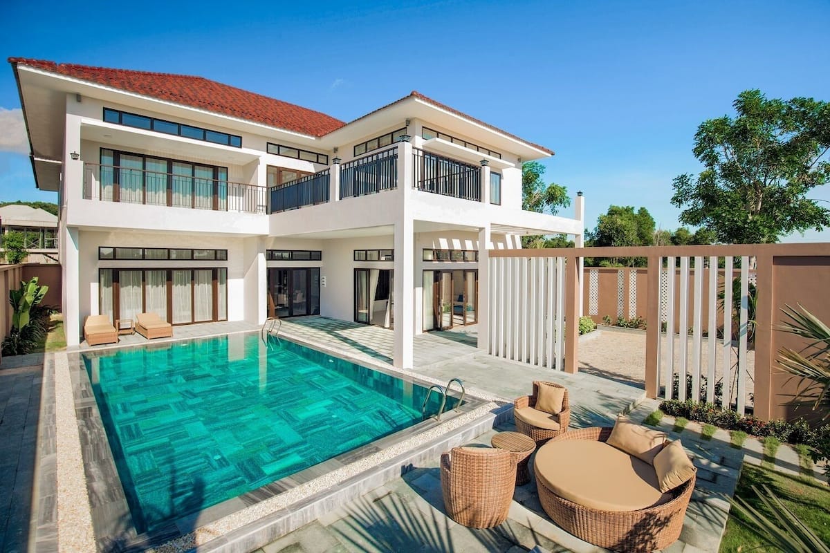 A two-story house with a swimming pool, outdoor seating, and a fenced garden.