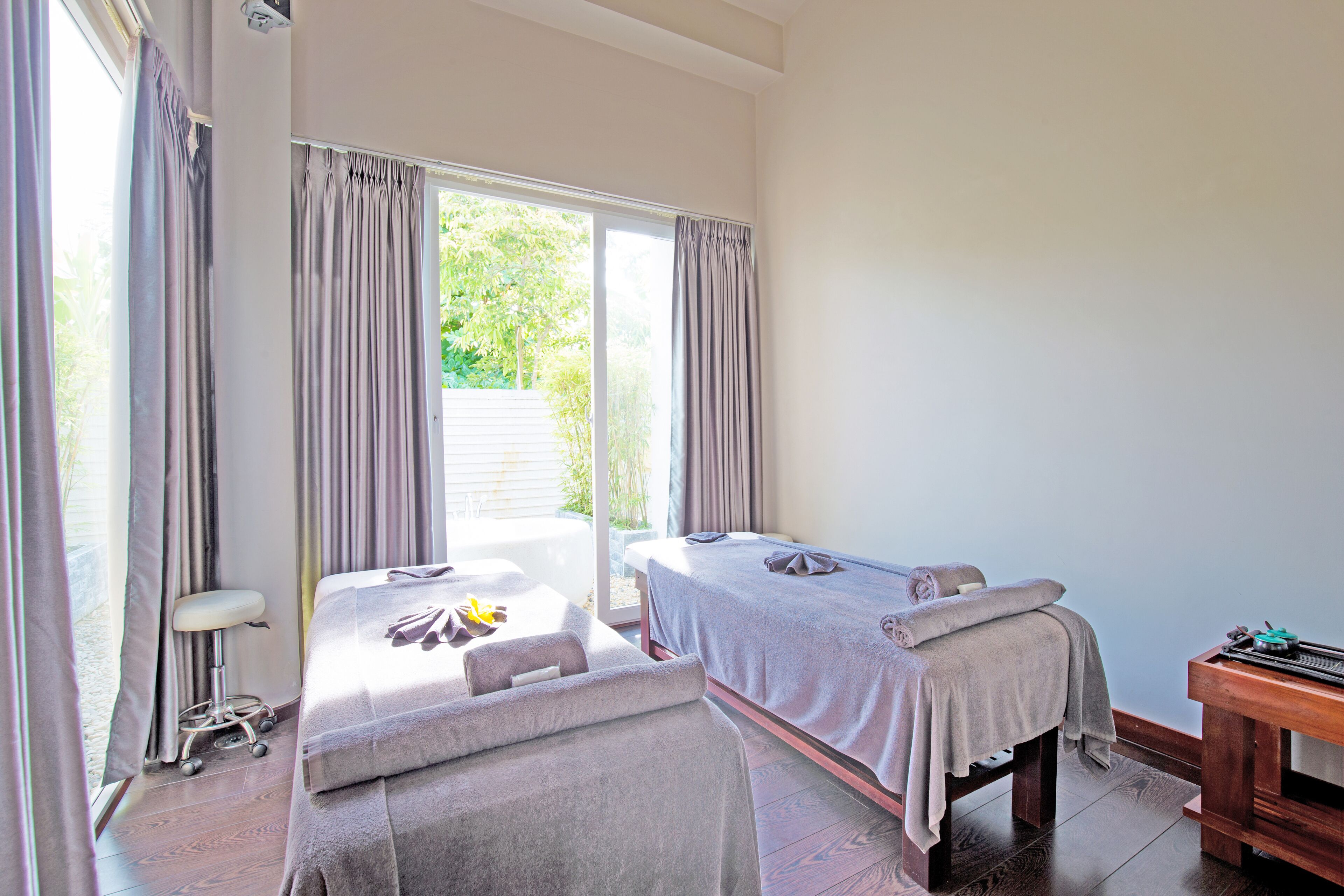 Un cuarto de spa con dos camillas de masaje, un banco de madera y una silla de masajes.