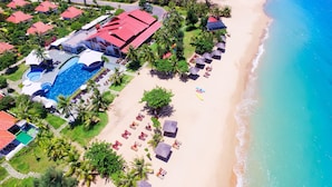 An aerial view of a resort with a swimming pool, beach area with umbrellas, and a beach house with a red roof. - Mercury Phu Quoc Resort & Villas - Free Airport Transfer (Phu Quoc)