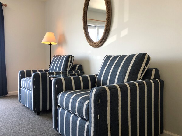 A room with striped armchairs, a lamp, and a mirror on the wall. - Knapps Narrows Marina & Inn (Sherwood)