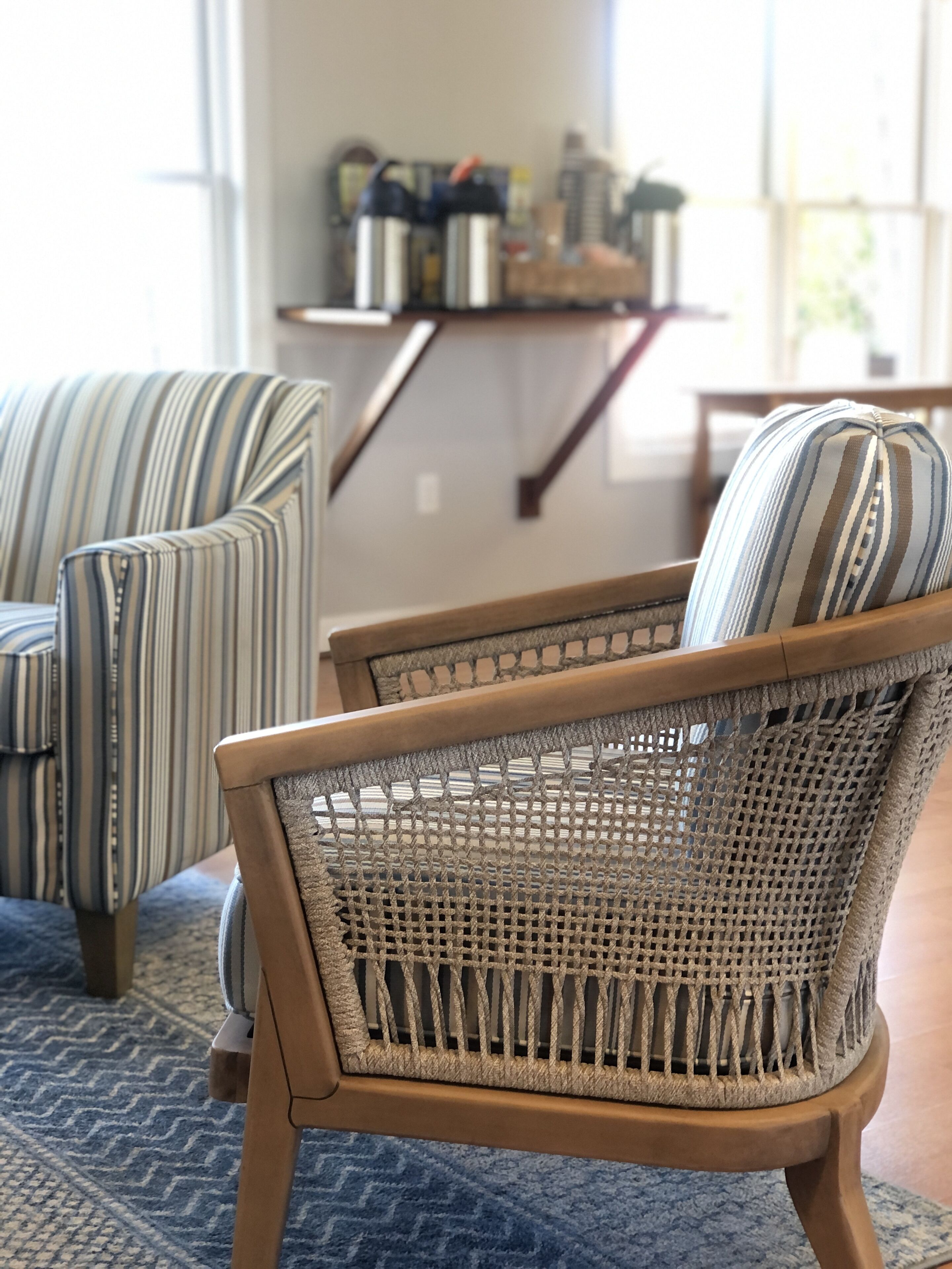 Una habitación con dos sillones a rayas y una silla de mimbre.