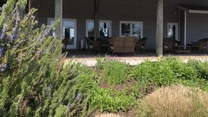 A covered patio area with wicker furniture and a view of a building with large windows. - Knapps Narrows Marina & Inn (Sherwood)