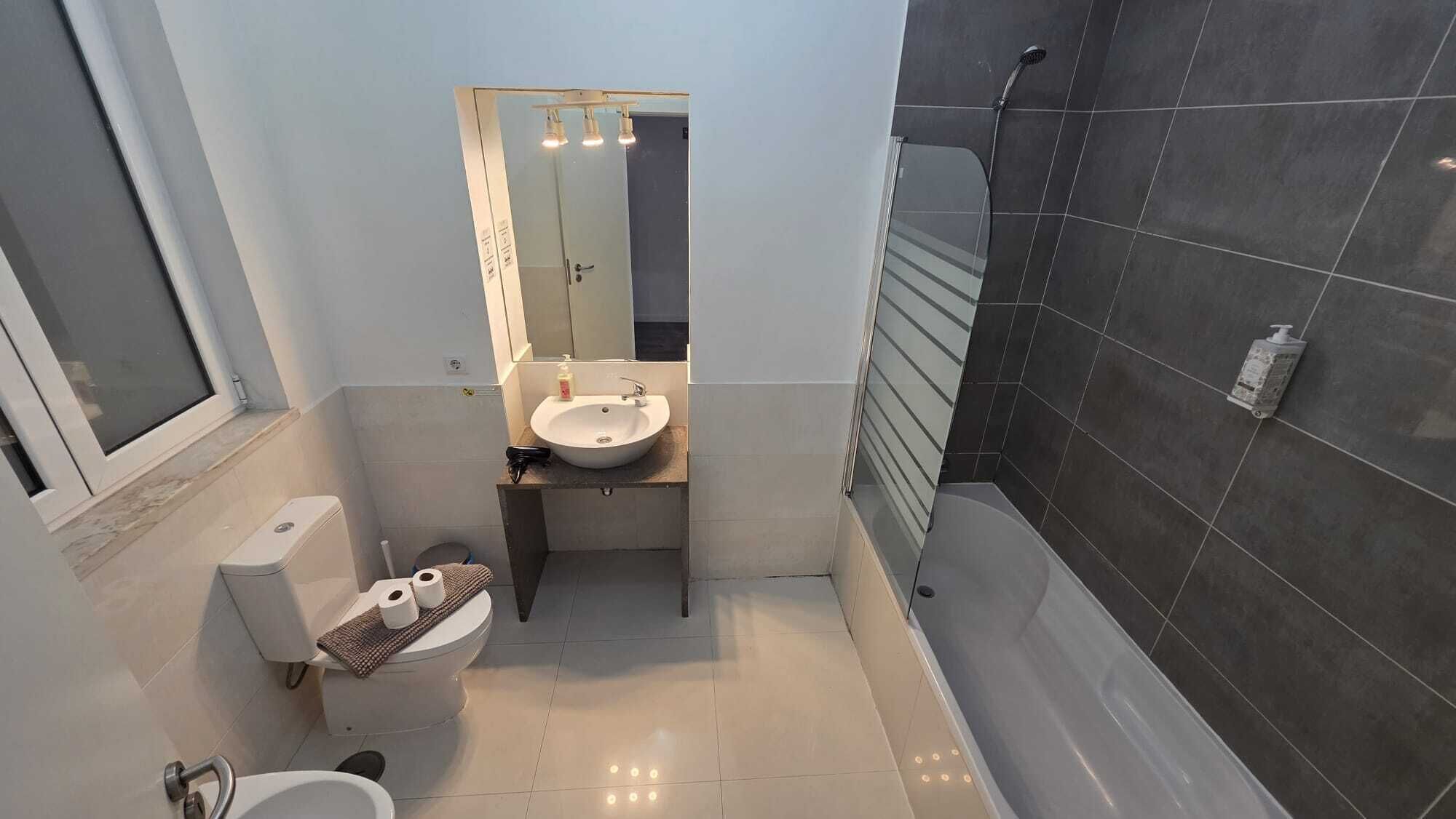 Casa de banho compacta com sanita, lavatório e chuveiro.