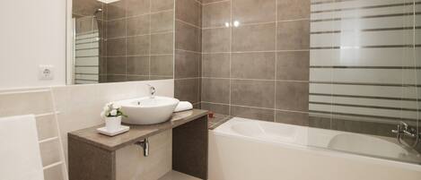 A modern bathroom with a bathtub, a sink, and a mirror.