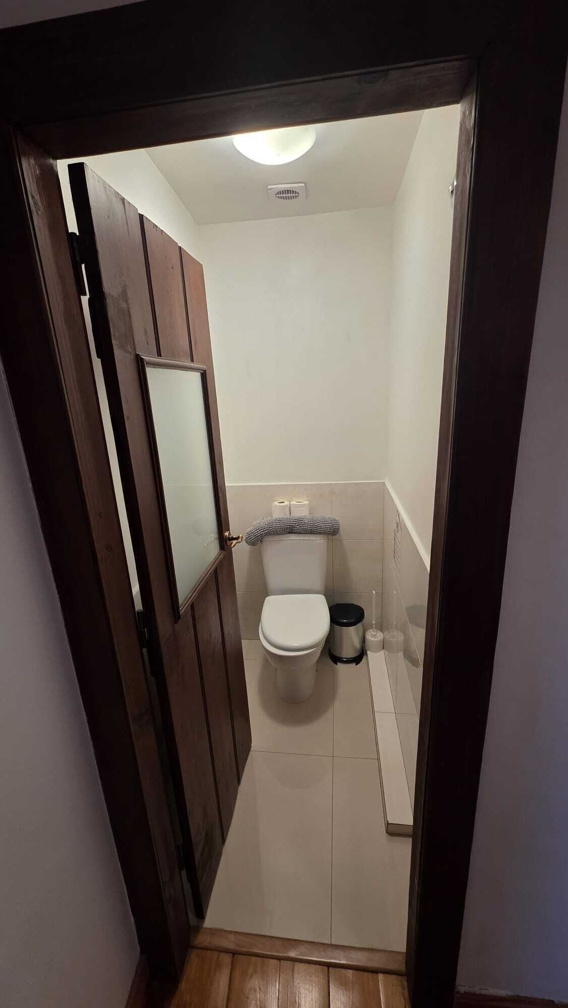 A small, narrow bathroom with a toilet, bidet, and a mirror on the wall.