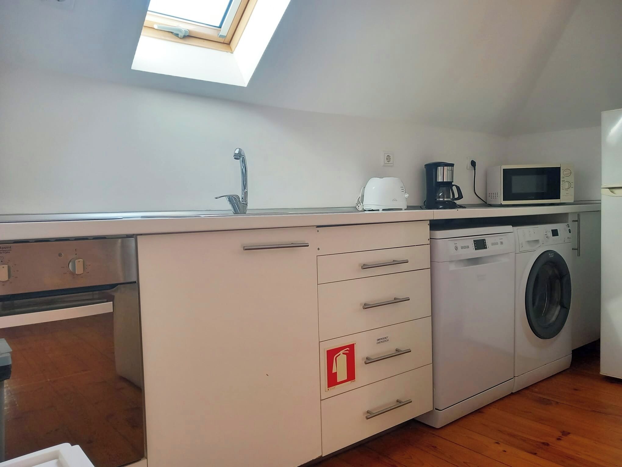 A compact kitchen with a built-in washing machine, a microwave, and a coffee maker.