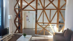 Una sala de estar moderna con una pared de acento de madera, un televisor de pantalla plana, una mesa de centro blanca y un sofá.