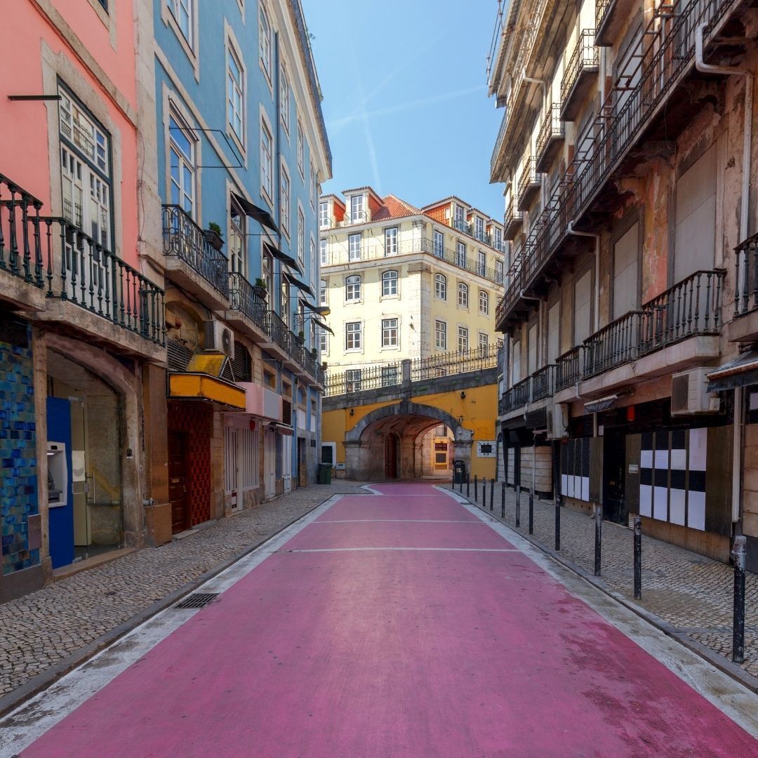 A narrow street with buildings on either side, a red bike lane, and a pedestrian walkway.