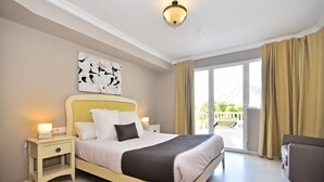 A bedroom with a bed, bedside tables, a nightstand, a ceiling light, a window with curtains, and a view of the outdoors. - Aparthotel Ola Blanca (Finestrat)