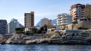 A coastal cityscape with multi-story buildings, rocky cliffs, and a clear sky. - Aparthotel Ola Blanca (Finestrat)