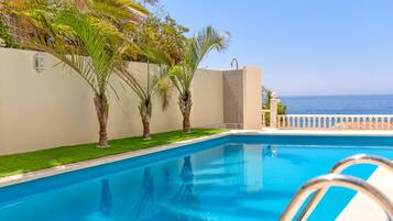 Relax by the serene pool surrounded by lush greenery and palm trees.