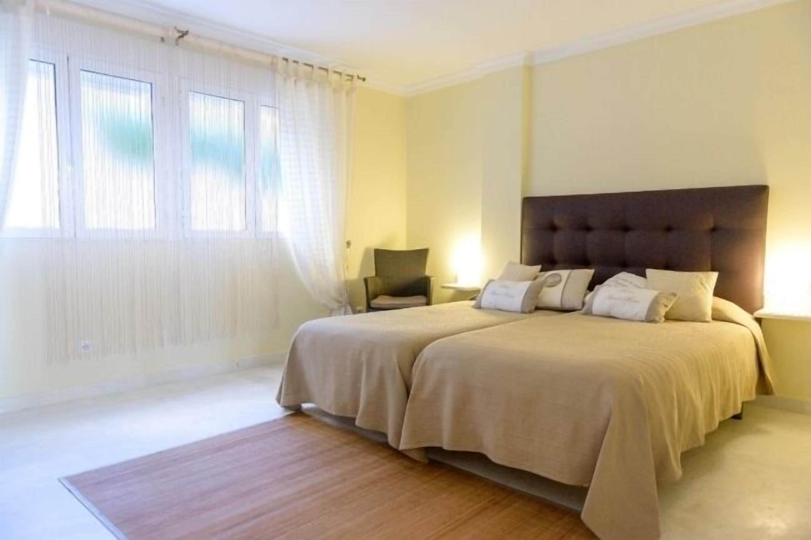 A double bed with a dark headboard, a bedside table with a lamp, and a window with curtains.