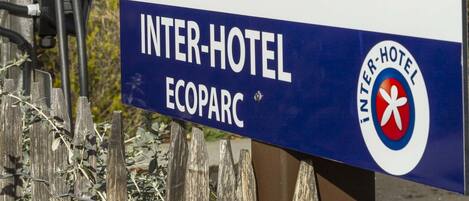 Señal de un Inter-Hotel Ecoparc con símbolos que indican una estación de carga y un sol.