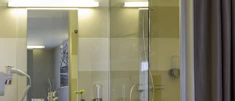 A modern bathroom with a glass shower enclosure, a vanity with a mirror, and a towel rack.