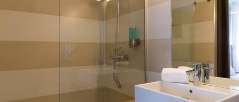 A modern bathroom with a glass-enclosed shower, a white sink, and a mirror.