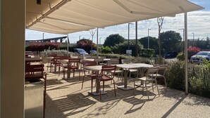 An outdoor café with tables and chairs under a large canopy.