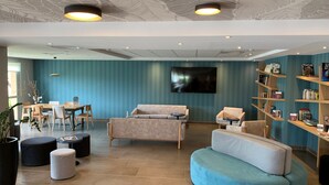A modern lounge area with seating, a flat-screen TV, and bookshelves.