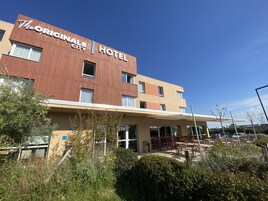 L'hôtel City, qui abrite l'établissement d'origine, se distingue par sa façade moderne, ses nombreuses fenêtres et son espace extérieur aménagé avec une zone de sièges couverte.