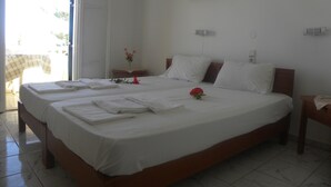 A large bed with white linens, a painting above it, and a small table with a vase of flowers. - Villa Thalia (Agios Nikolaos)