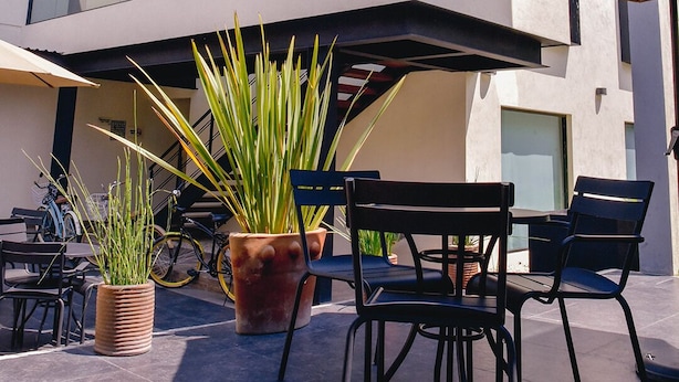 Een moderne buitenzitplaats met glazen wanden, potplanten en tuinmeubilair.