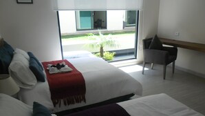 Een moderne hotelkamer met een groot bed, een bureau en uitzicht op een groen gebied buiten.