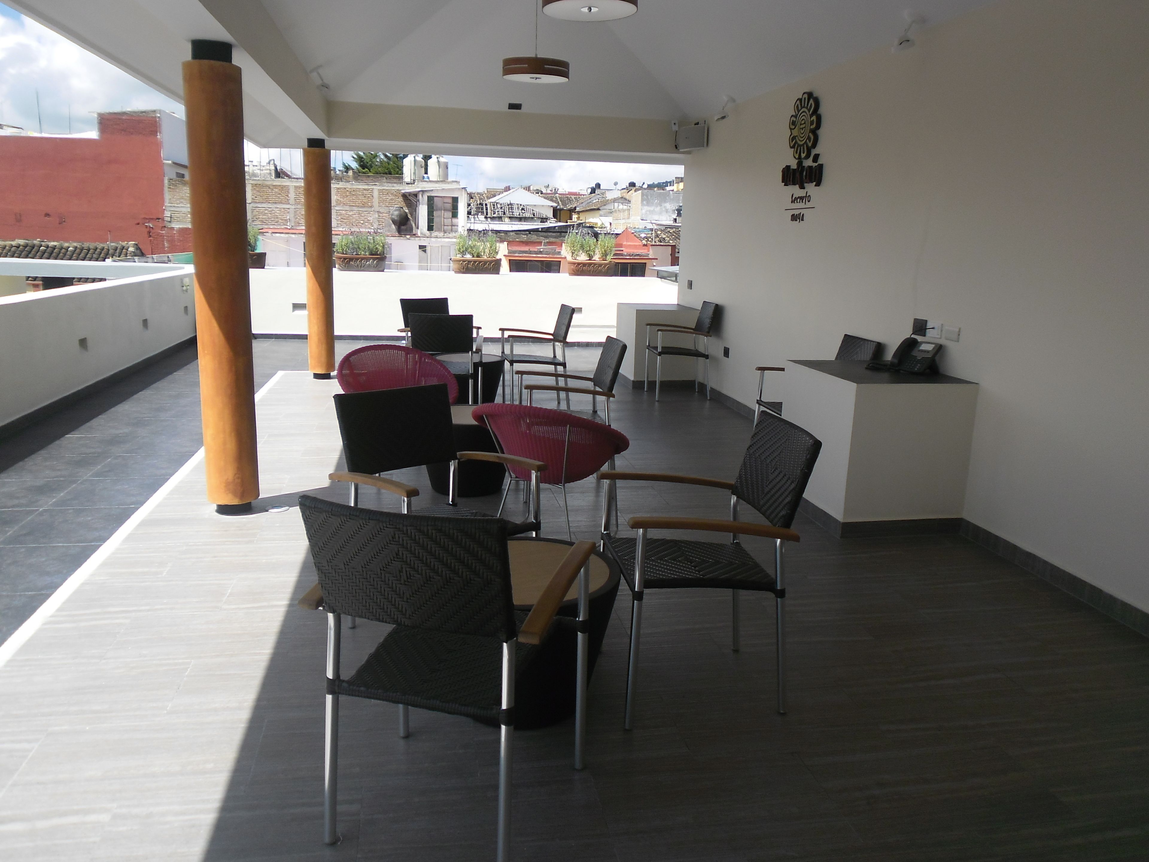 A rooftop terrace with modern furniture, including chairs and a table, and a reception desk.