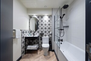 Un baño pequeño con inodoro, lavamanos, espejo y ducha.