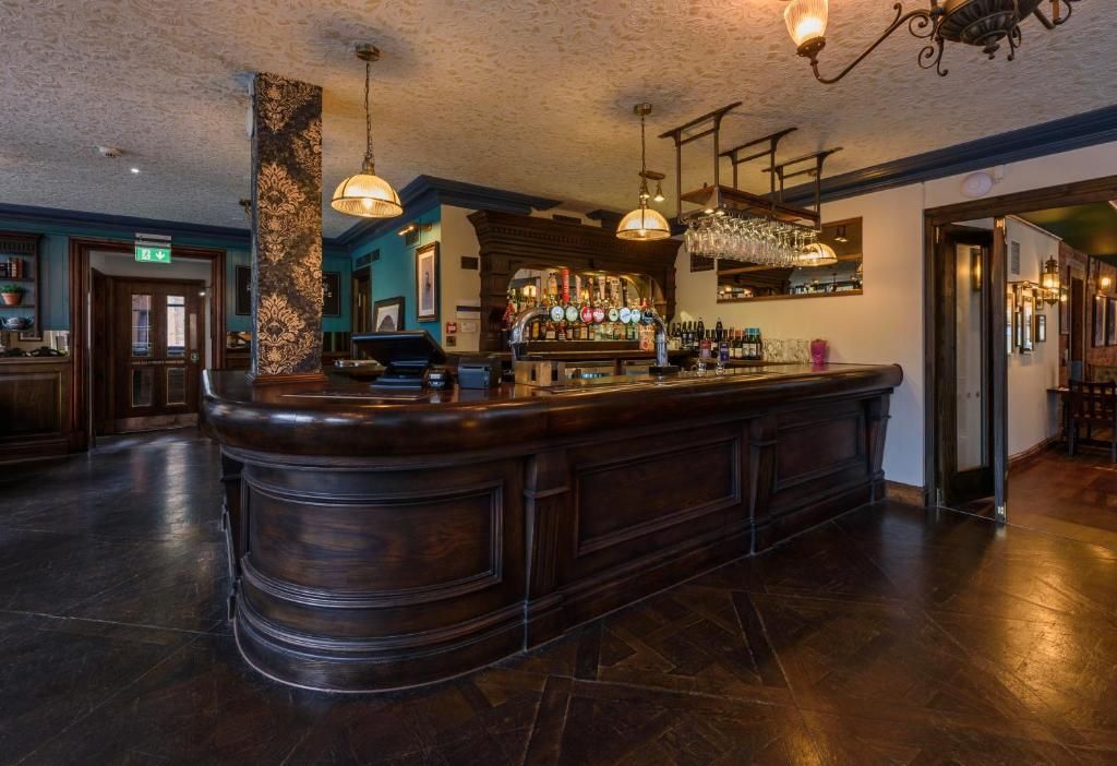 A bar area with a central bar counter, overhead lighting, and a bar stocked with bottles.