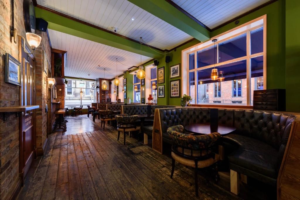 Interior acogedor de restaurante con pisos de madera, asientos de cuero y ventanas amplias.