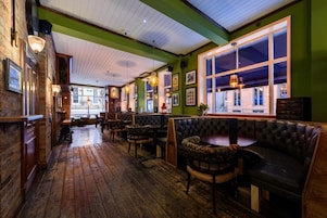 Interior acogedor de restaurante con pisos de madera, asientos de cuero y ventanas amplias.