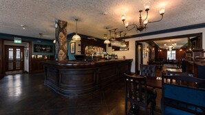 A bar area with a wooden counter, bar stools, and hanging lights. - The Abel Heywood (Manchester)