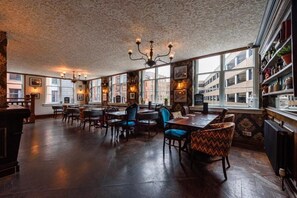 A restaurant with a high ceiling, patterned wallpaper, and a chandelier. Tables and chairs are arranged for dining. - The Abel Heywood (Manchester)