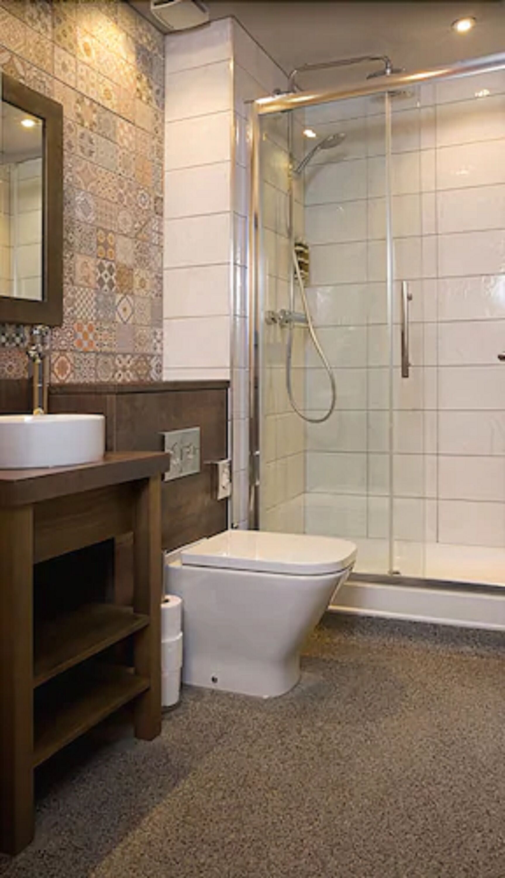 A bathroom with a tiled shower, a sink, and a toilet.