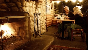 A cozy log cabin interior with a stone fireplace, wooden furniture, and a rustic ambiance. - Silver Fork Lodge and Restaurant (Brighton)