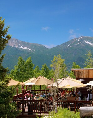Un restaurante con terraza al aire libre y vistas a un paisaje montañoso.