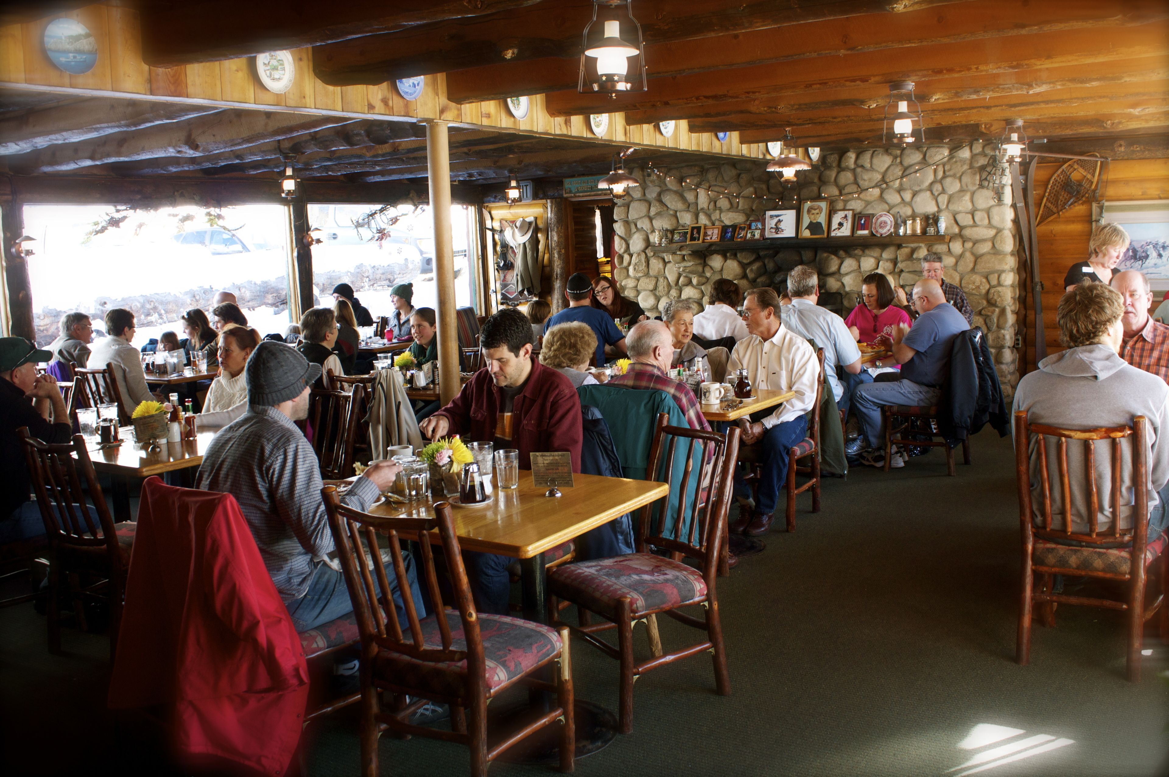 A restaurant with wooden interiors, stone walls, and patrons dining.