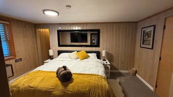 A bedroom with a bed, a television mounted on the wall, a bedside table with a lamp, and a sign on the wall.