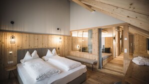 A modern bedroom with a large bed, a bench, and a walk-in closet. - Autentis (Rasun Anterselva)