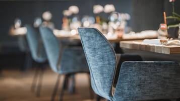 Una hilera de sillas tapizadas en azul con una mesa de madera en un restaurante.