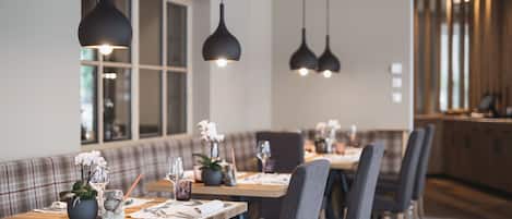 Un comedor moderno con una mesa larga, sillas tapizadas en gris e iluminación colgante.