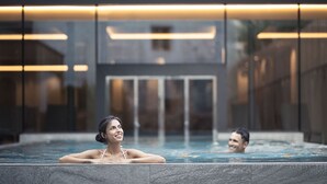 A modern indoor swimming pool with a glass enclosure, a visible door, and a minimalist architectural design. - Autentis (Rasun Anterselva)