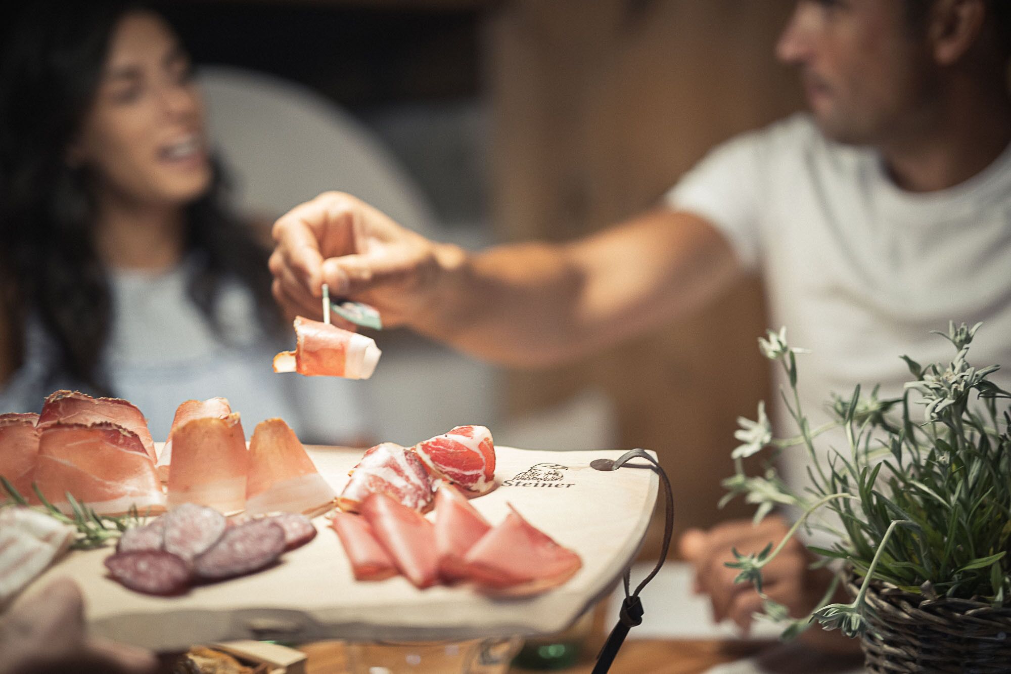 A table with various meats and a bottle of wine.